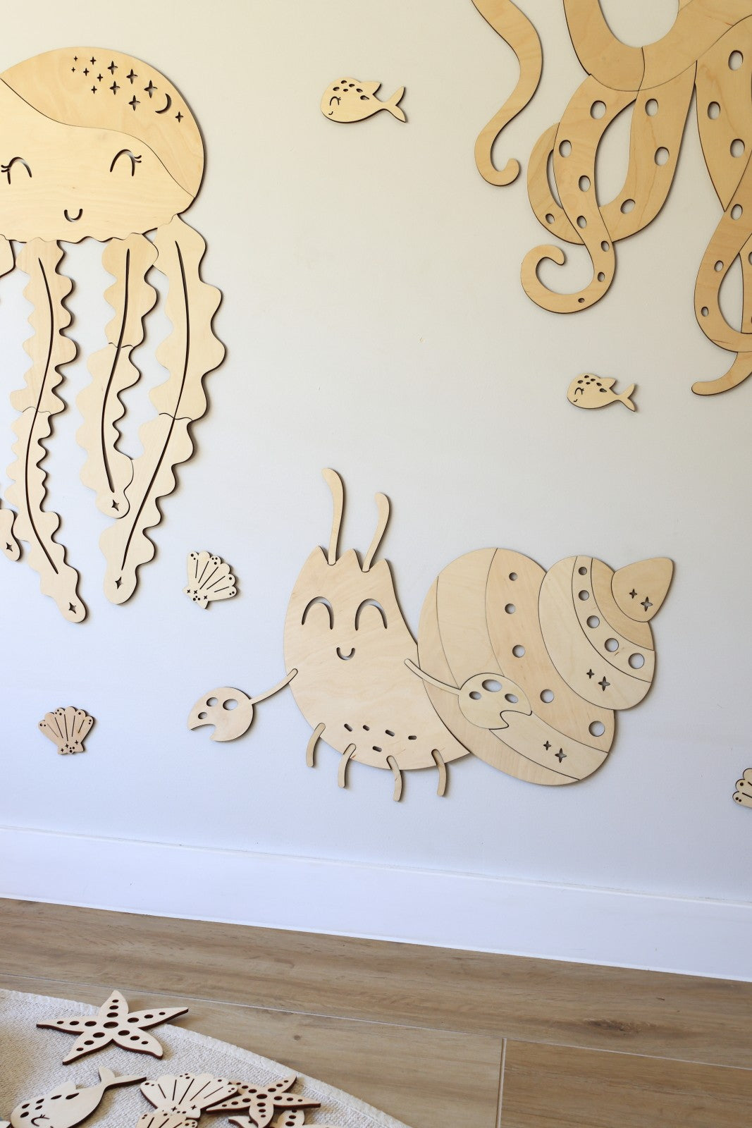 Décoration murale crabe en bois installée dans une chambre bébé sur le thème de l'océan avec animaux marins en bois.