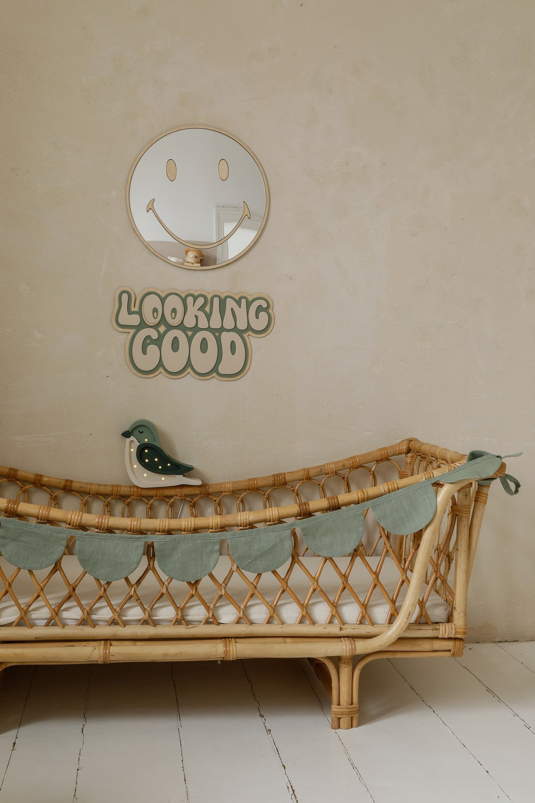 Miroir en bois pour chambre d'enfant suspendu au-dessus d'un lit dans une décoration douce et naturelle. 