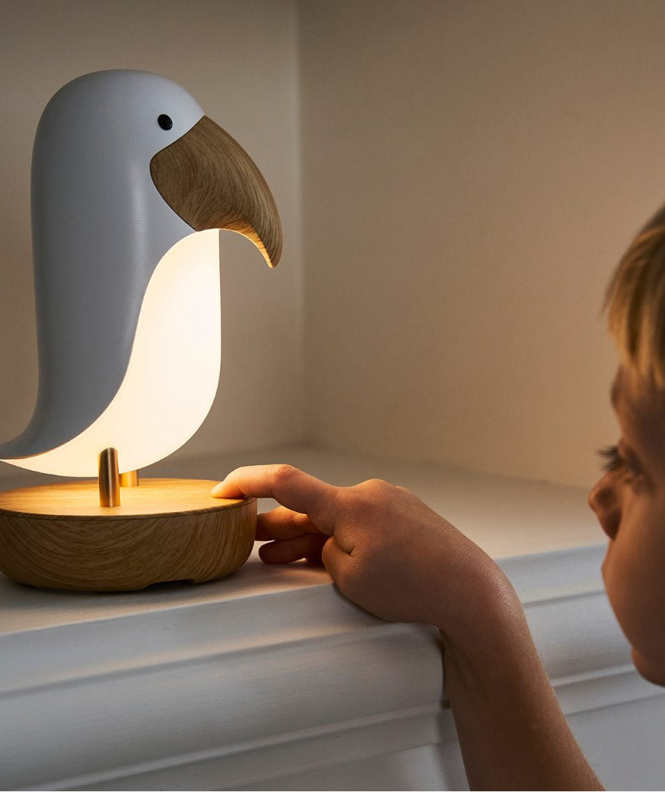 Veilleuse oiseau blanc en bois installée sur une table de chevet dans une chambre bébé