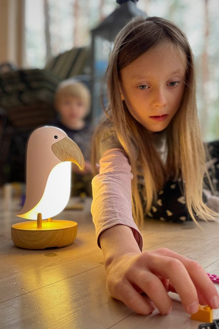 Enfant utilisant une veilleuse oiseau avec enceinte avant le coucher